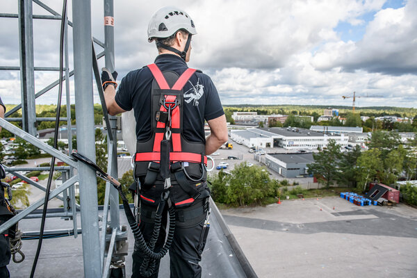 A CERTEX Lifting employee wearing the Aspire sustainable harness stands on scaffolding, looking out over the horizon.