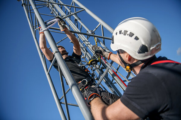 Two CERTEX Lifting employees wear the Aspire sustainable safety harness while scaling scaffolding.